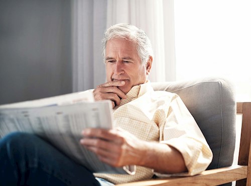 Retired man reading newspaper
