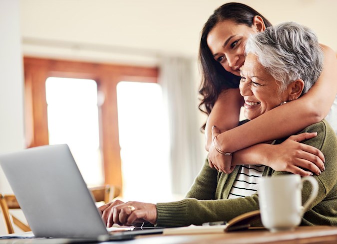 Daughter hugging mom looking at laptop