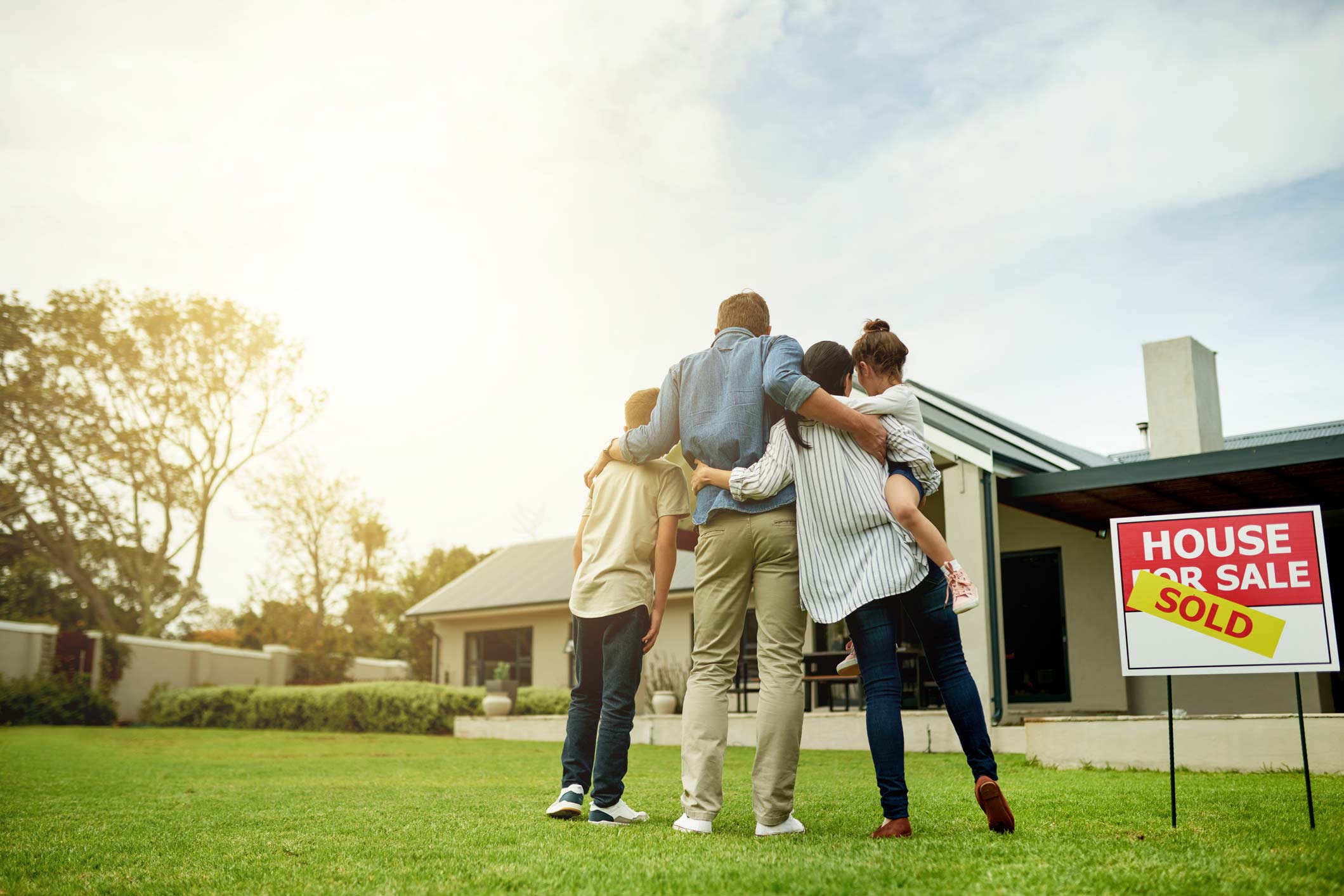 family hugging in front of home