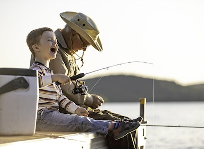 A grandfather fishes with grandson.