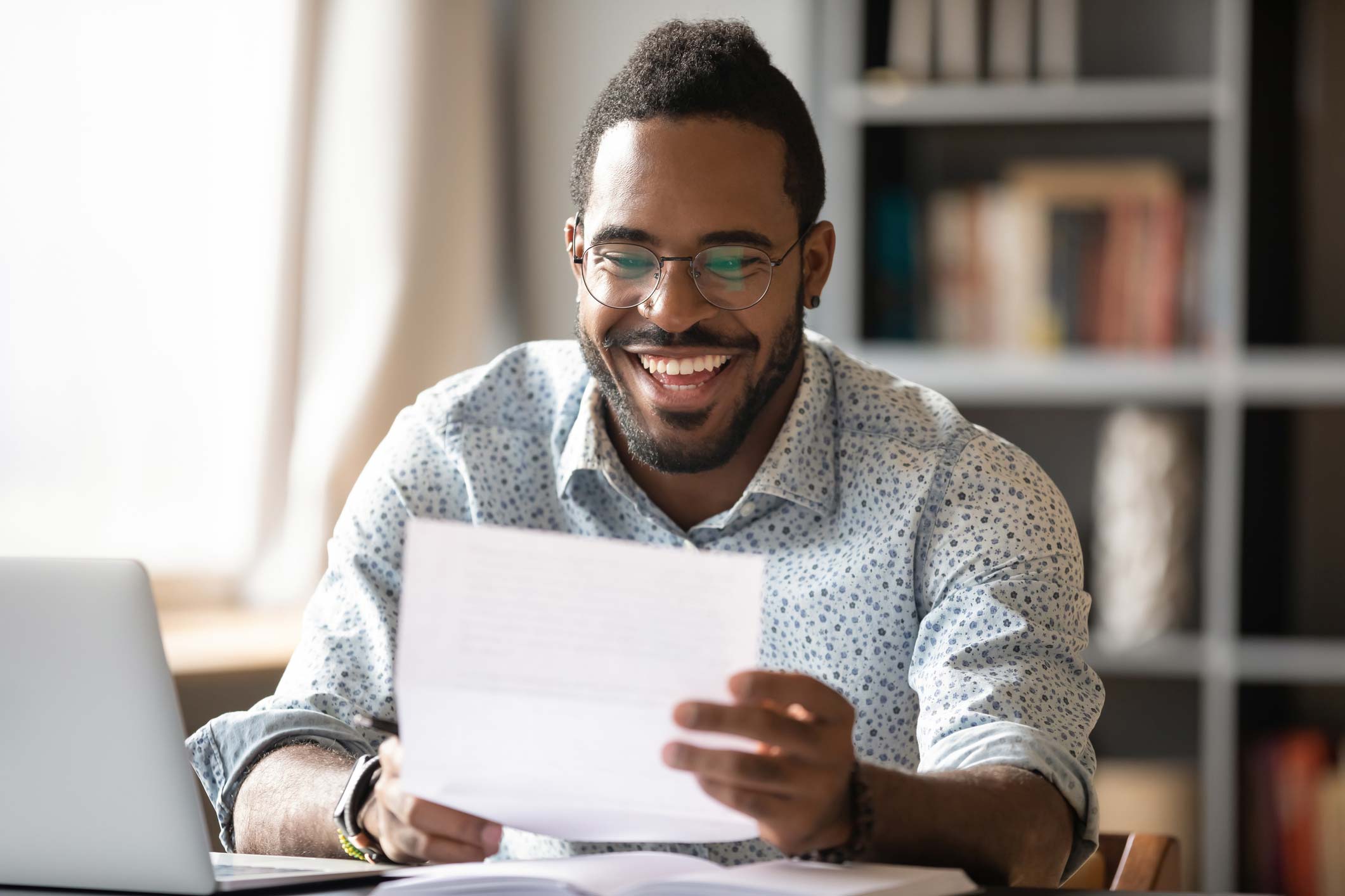 Young black man smiling while reading report