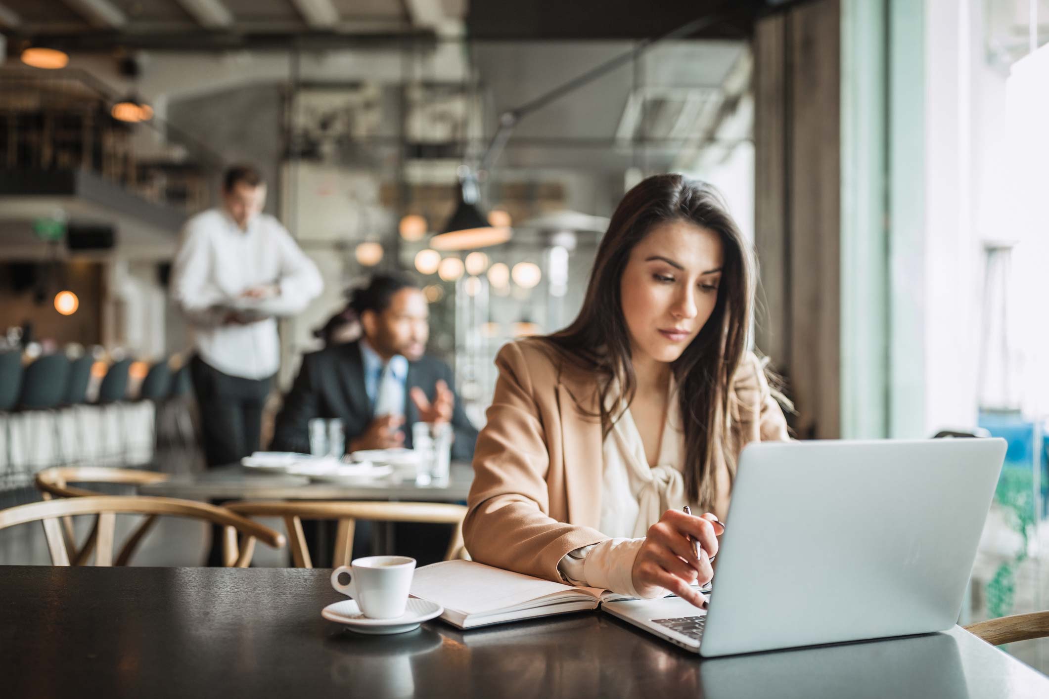 A woman looks at a laptop in a coffee shop